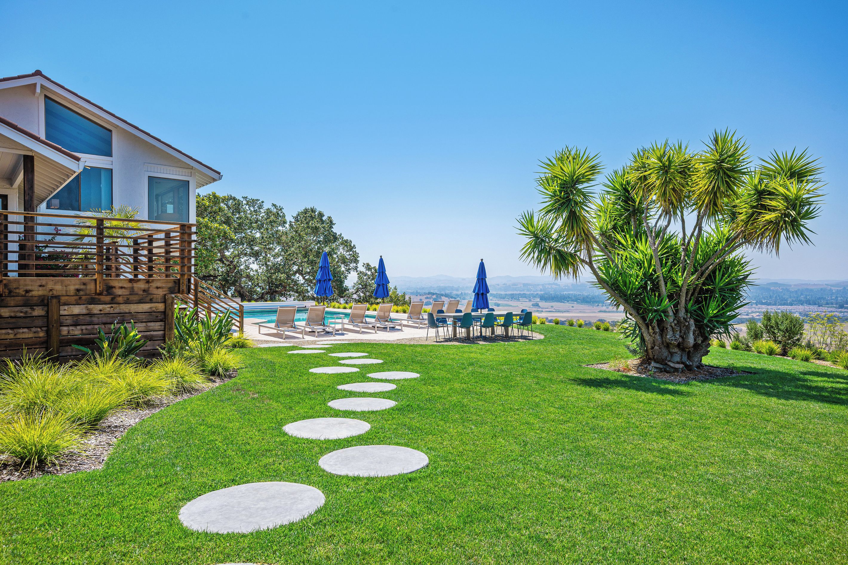 A modern house with a pool, outdoor seating, and a clear view of the landscape.