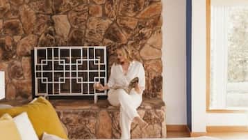 Guests can relax on the bed, surrounded by a geometric artwork and a stone wall.