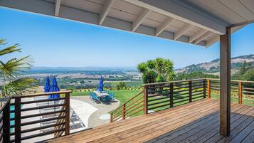 Una terraza de madera con vistas a un valle y colinas.
