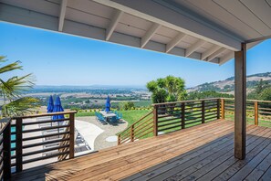 Une terrasse en bois offrant une vue sur une vallée et des collines.