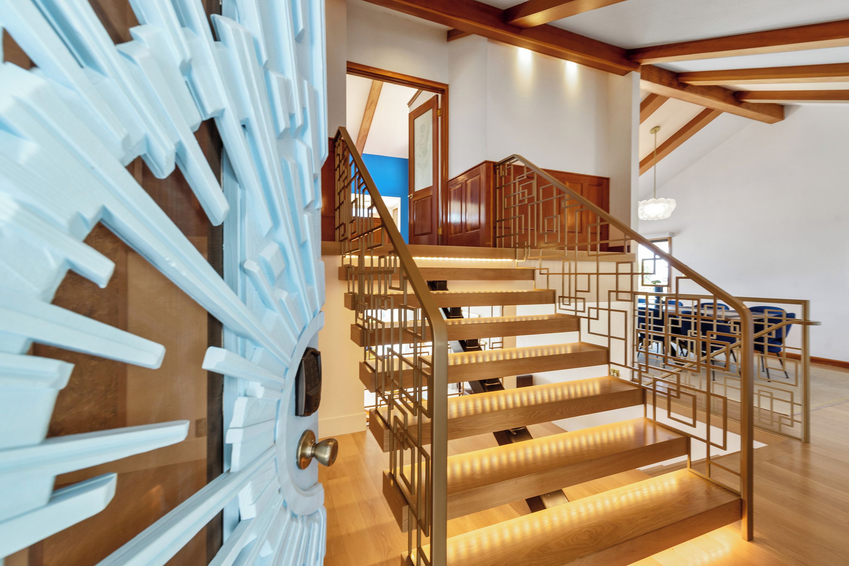 Una escalera moderna con escalones de madera y barandales de metal, que sube a un piso superior.