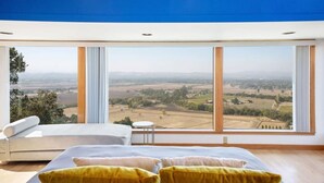 Une chambre dotée d’une grande fenêtre donnant sur un paysage rural.
