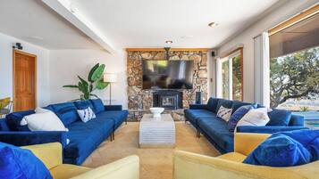 Una sala de estar con pared de piedra, televisor de pantalla plana y chimenea.