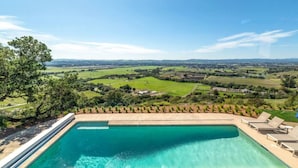 Une piscine offrant une vue sur un paysage verdoyant et des collines lointaines.