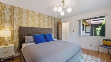 Een slaapkamer met een groot bed, een nachtkastje, een lamp, een raam met uitzicht en een modern plafondlamp.