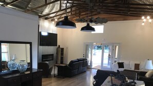 A spacious living room with a fireplace, leather sofas, a TV, and a large mirror. - Dry Creek Ranch ~ Pool, HotTub, & Game Barn! (Healdsburg)