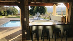 An outdoor hot tub area with a wooden deck, a pool, and a view of the surrounding landscape. - Dry Creek Ranch ~ Pool, HotTub, & Game Barn! (Healdsburg)
