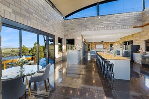A modern kitchen with a large island, a dining area with a view, and a spacious layout. - Tyalla Lodge (Mudgee)