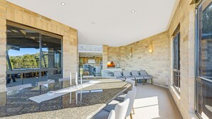 Un interior moderno con una larga mesa de comedor, asientos cómodos y un fondo de pared de piedra.