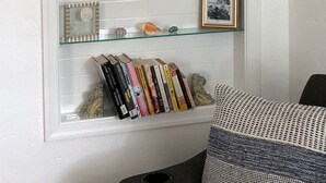 A wall-mounted shelf with decorative items, a framed picture, and a collection of books.