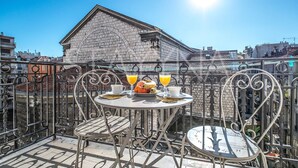 Terraço no telhado com uma mesa posta para dois, dois copos de suco de laranja e um prato de comida.