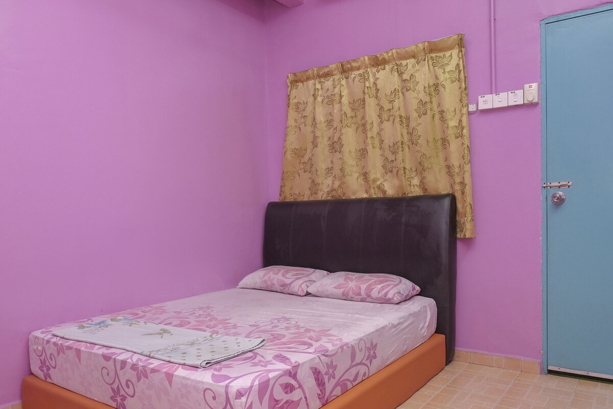A bedroom with a bed, a door, and a window with curtains.