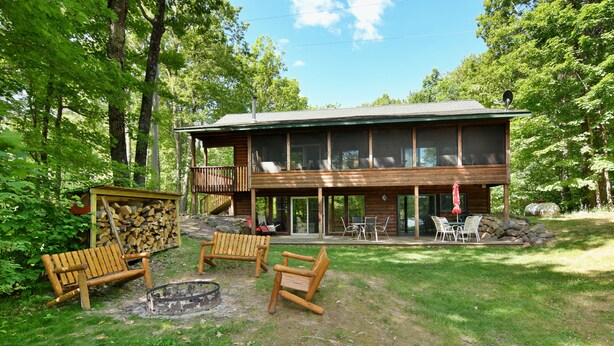 Eine Hütte mit einer Terrasse, Sitzgelegenheiten im Freien und einer Feuerstelle.