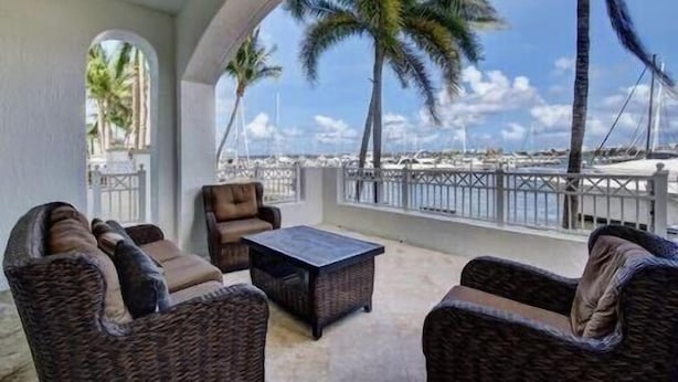 A covered outdoor seating area with wicker furniture and a view of the marina. - Resort living (Lantana)