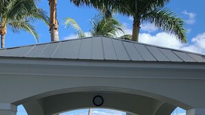 A covered outdoor area with a pool, palm trees, and a view of boats and buildings in the background. - Resort living (Lantana)