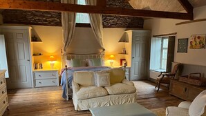 Ein gemütliches Schlafzimmer mit Baldachinbett, einer Sitzecke mit Bank und Holzboden.