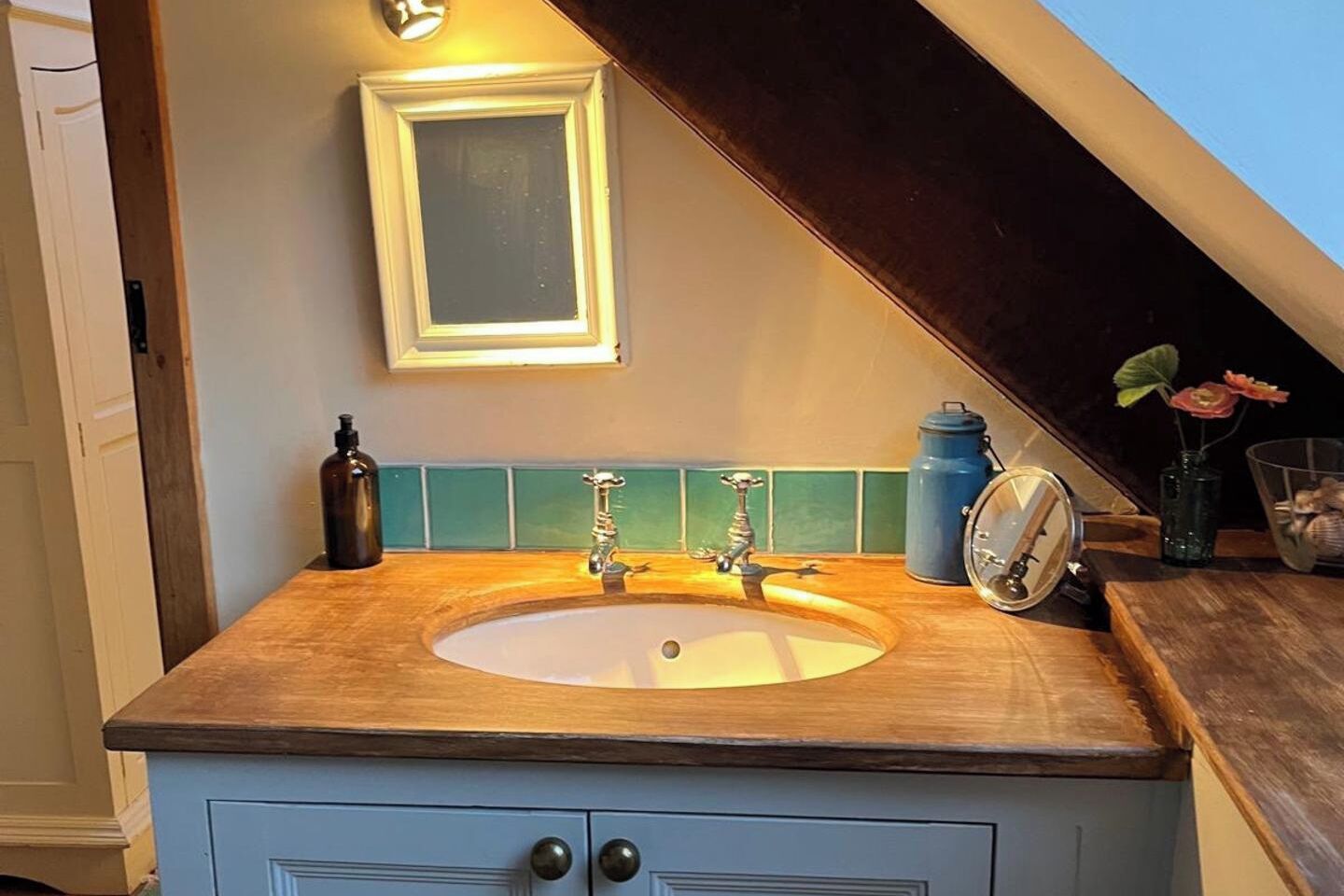 Ein Badezimmer mit einem Holzbadezimmerhocker, einem Waschbecken, einem Spiegel und einer Uhr.