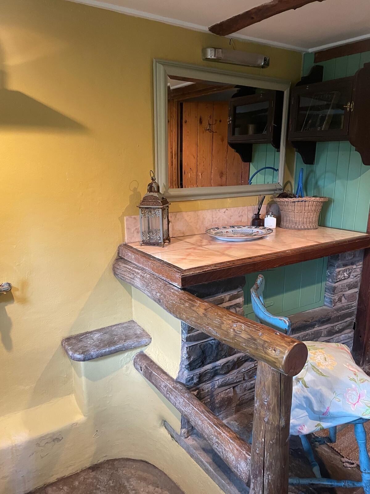 Ein rustikales Badezimmer mit einer hölzernen Bank, einem Waschbecken und einem Spiegel.