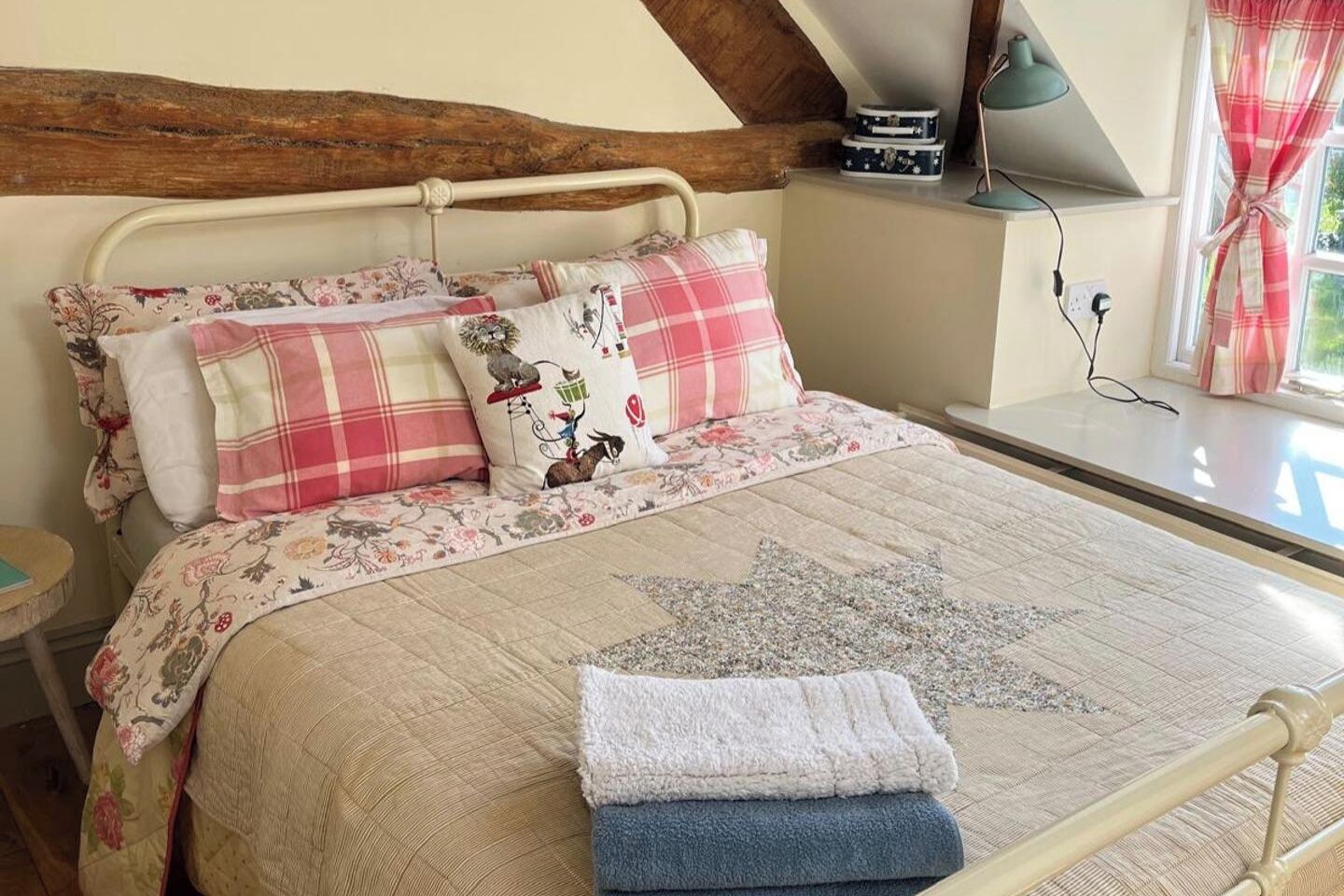 Una cama con ropa de cama floral, almohadas a cuadros y un plaid con forma de estrella.