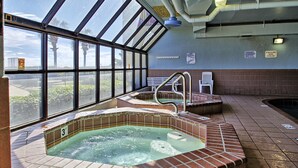 Ein Whirlpoolbereich mit Blick auf Palmen und einen klaren Himmel, durch große Fenster sichtbar.