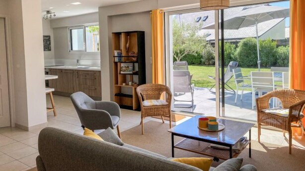 Een moderne woonkamer met een bank, fauteuils, een salontafel en een boekenkast.