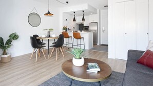 A modern living room with a round coffee table, a sofa, and a dining area with chairs and a small island.