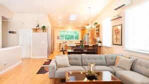 Uma sala de estar moderna com um sofá seccional cinza, uma mesa de centro de madeira e uma área de jantar com uma mesa e cadeiras de madeira.