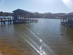 Un lago con muelles de madera y una pequeña construcción tipo cabaña en uno de los muelles.