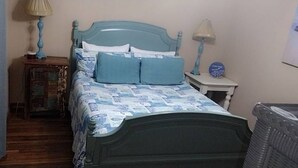 A bedroom with a bed, a nightstand, a lamp, and a dresser.