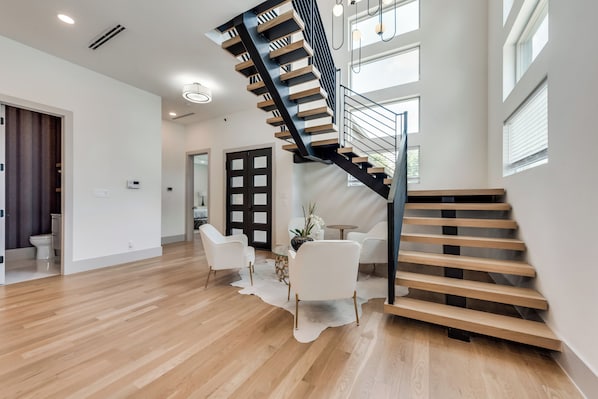 Een modern interieur met een houten trap, witte meubels en een glazen deur.