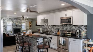 A modern kitchen with a central island, stainless steel appliances, and a stone backsplash.