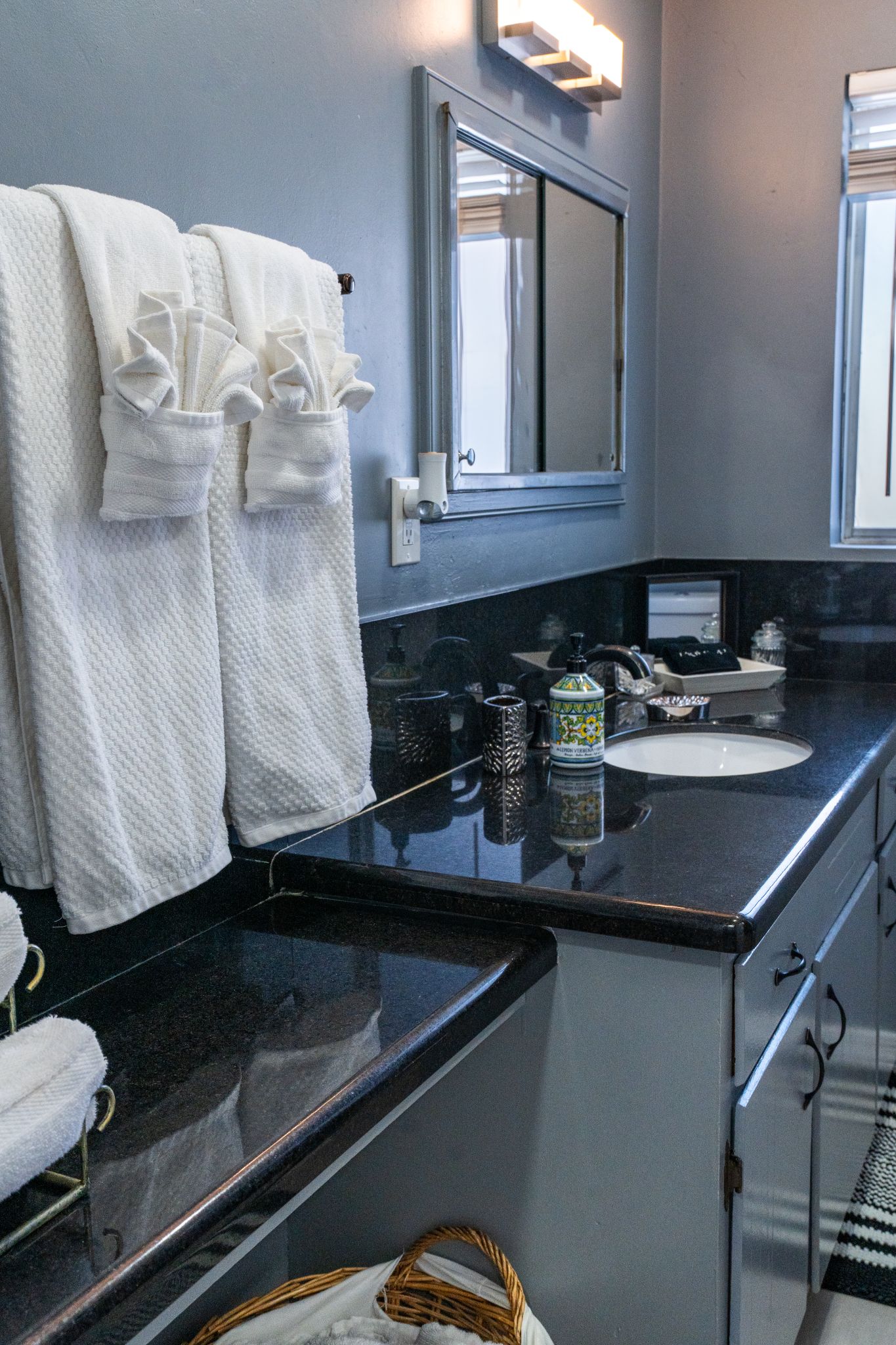 A bathroom with a black countertop, a white sink, and two towels hanging on a rack.