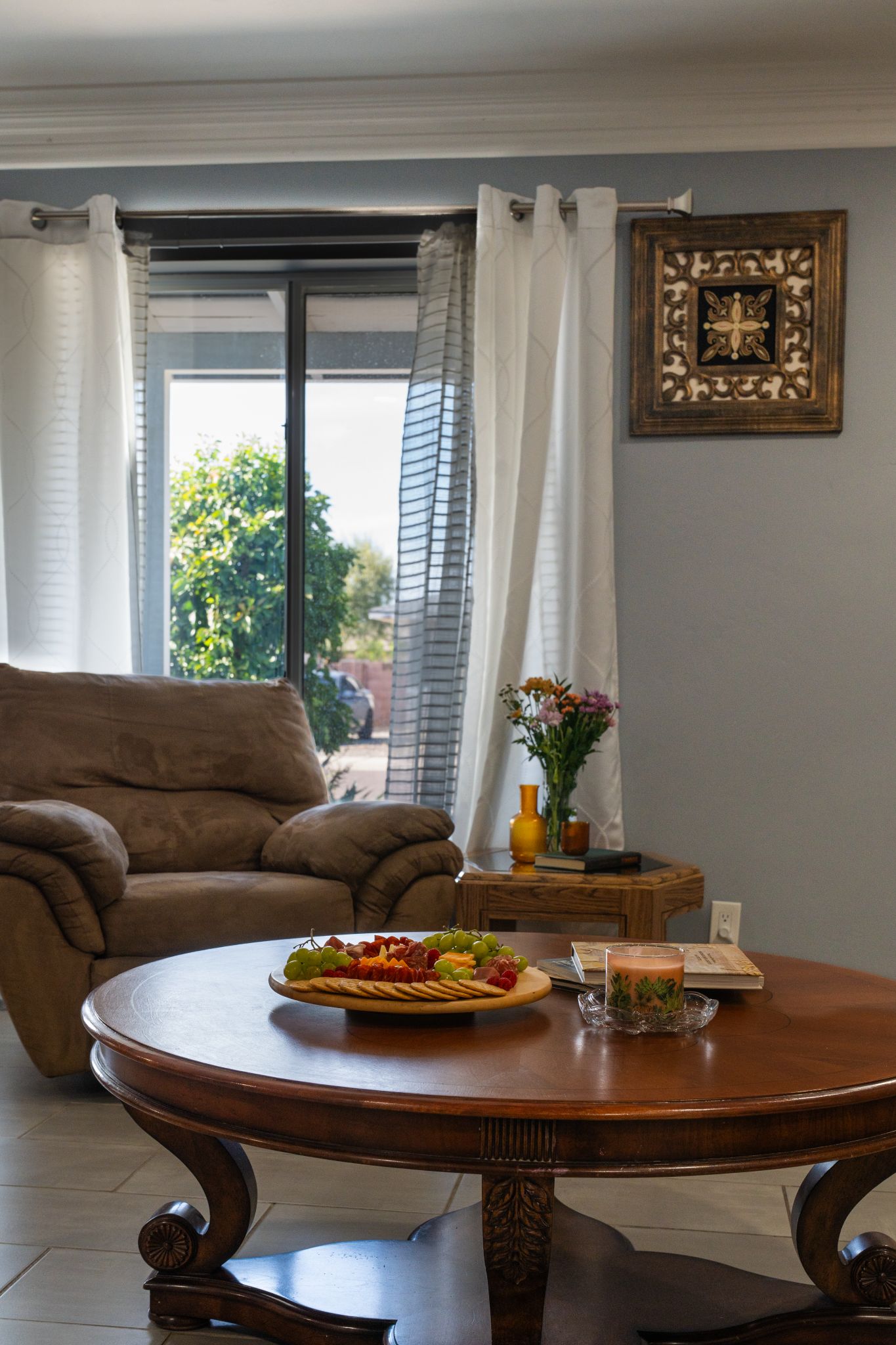 A dining area with a round table, a sofa, and a window with curtains.