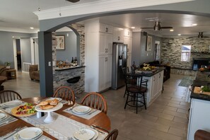 Een ruime keuken met een centraal eiland, inbouwapparatuur en een eethoek met een tafel gedekt voor vier personen.