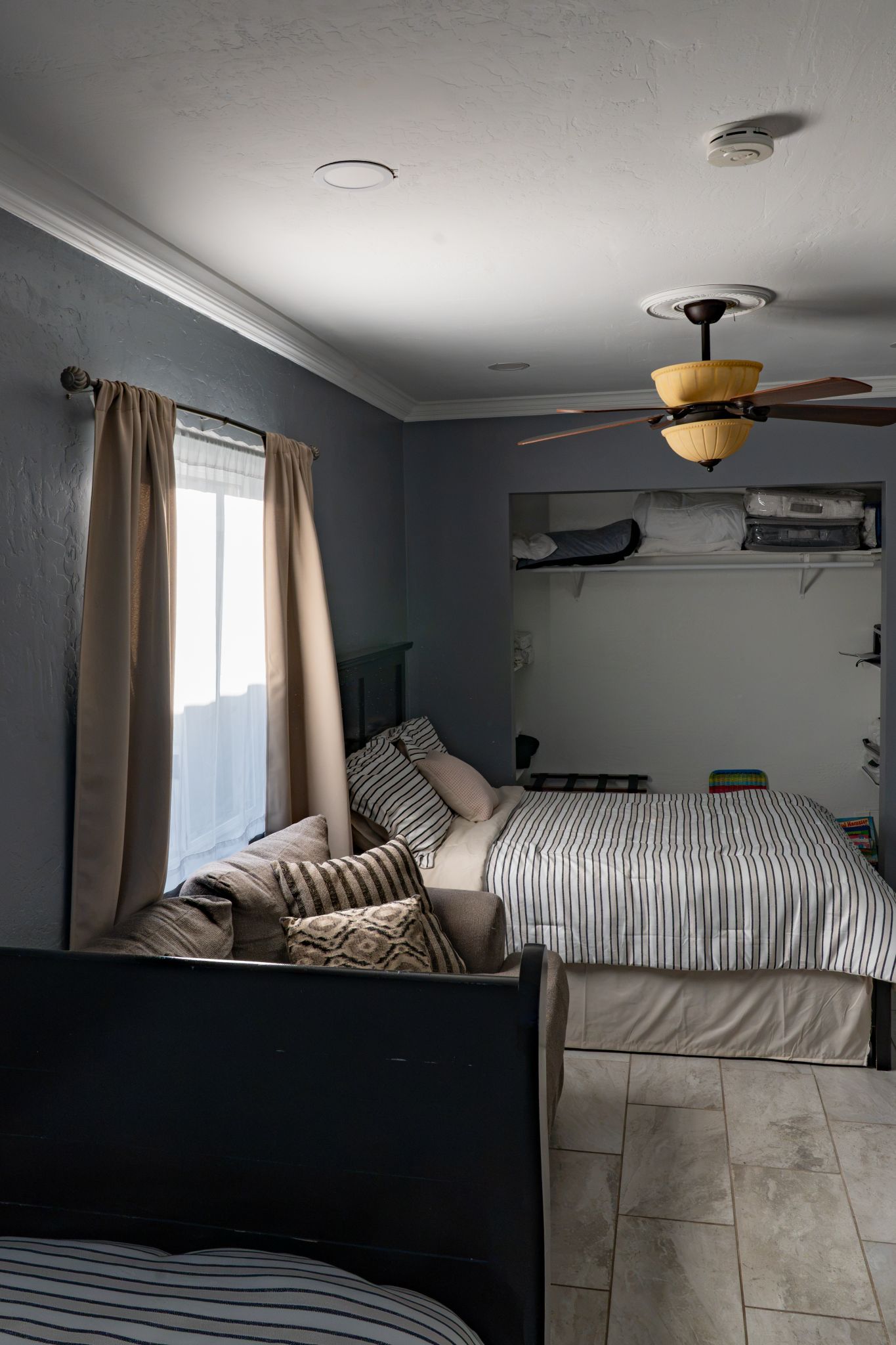 A bedroom with a bed, a ceiling fan, and a window with curtains.