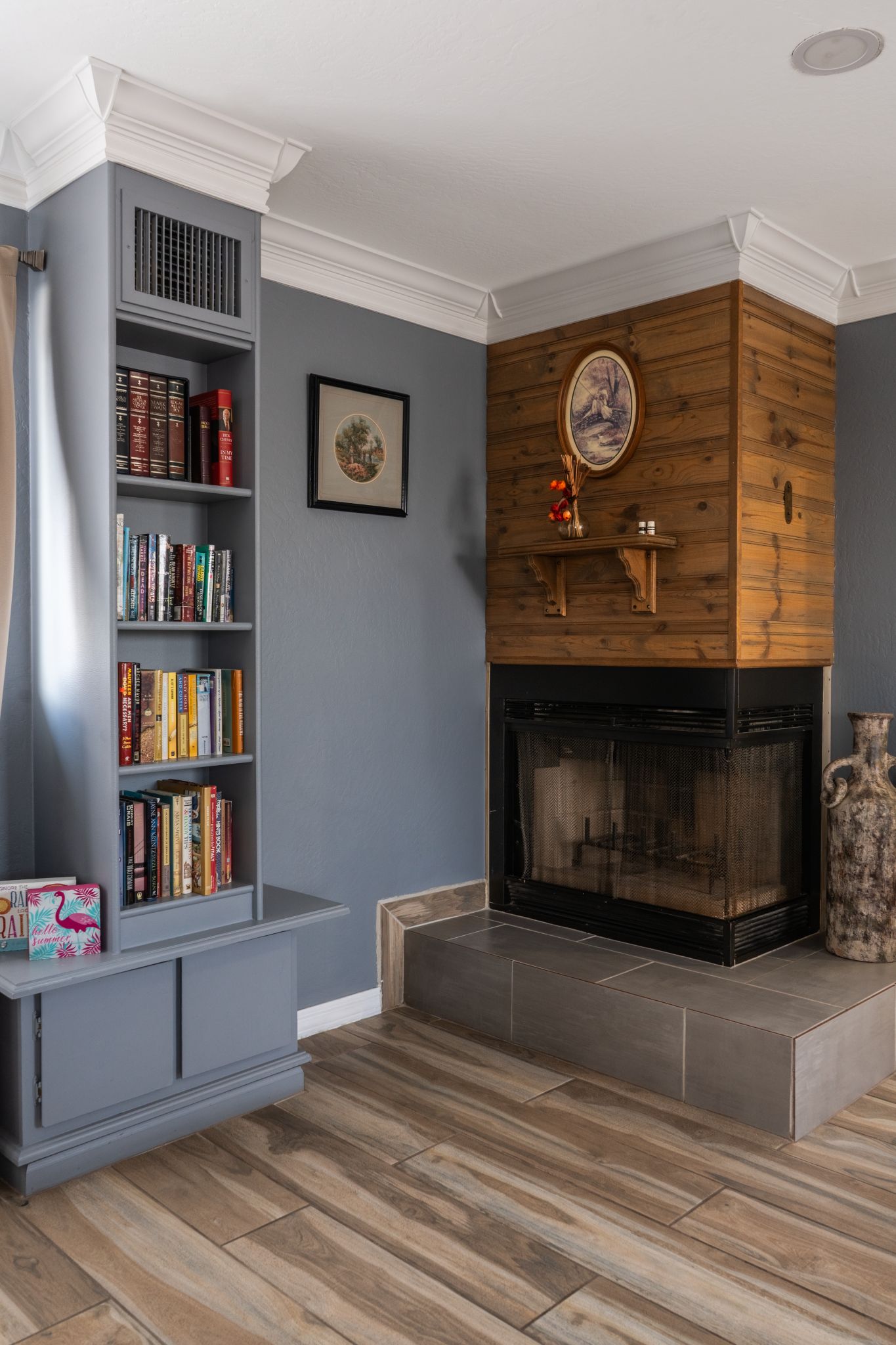 A living room with a fireplace, bookshelves, and a decorative vase.