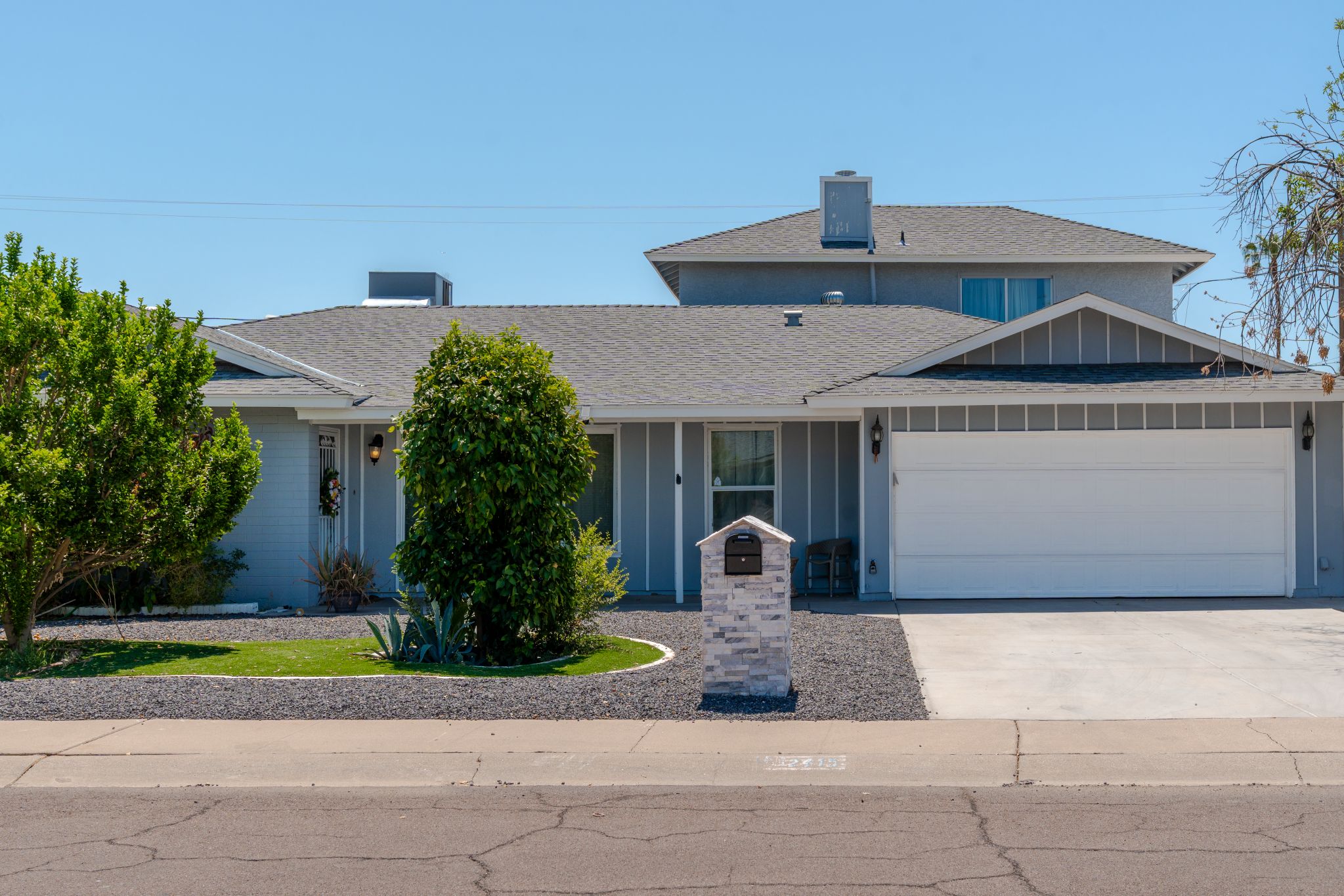A two-story house with a garage, a stone mailbox, and a well-maintained lawn.