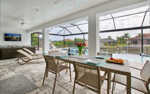 Un espace repas moderne avec une table en verre, des chaises et une vue sur une piscine.