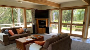 A spacious living room with a large TV, comfortable seating, and a view of the outdoors. - Black Bluff View Retreat - a large comfortable 5 bedroom house on 40 hectares. (North Motton)