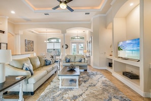 A spacious living room with a large television, two sofas, a coffee table, and a decorative rug. - Sunset Views Over Infinity Pool w/ Boat Dock (Cape Coral)