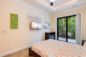 A bedroom with a bed, a television, and a sliding glass door leading to a balcony. - Sunset Views Over Infinity Pool w/ Boat Dock (Cape Coral)