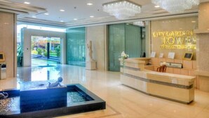 A hotel reception area with a reception desk, a decorative fountain, and a view of the outside.