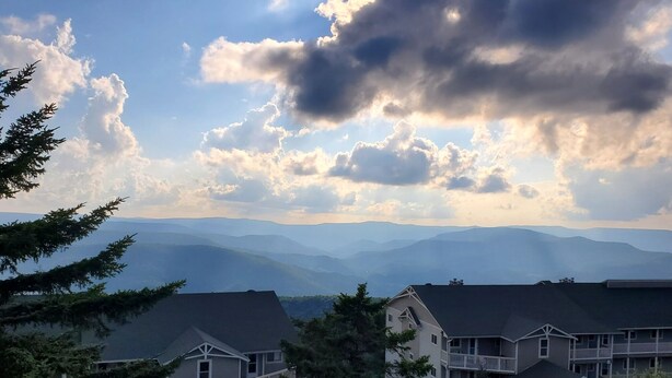 A residential area with multiple two-story houses, a parking lot, and a mountainous backdrop. - 3bd/2ba Summit Condo Close to Village and on shuttle route.  (Snowshoe)