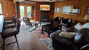 A cozy living room with a fireplace, a television, and a ceiling fan. There are several chairs and a sofa. - 3bd/2ba Summit Condo Close to Village and on shuttle route.  (Snowshoe)