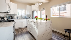 A modern kitchen with white cabinetry, a marble island, and a built-in oven. - 1stResorts.com Water Views! 2 FAMILY Villas Amalfi/Bellagio on 1 property! (San Diego)