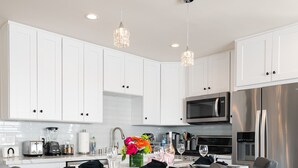 A modern kitchen with white cabinets, stainless steel appliances, and a central island with bar stools. - 1stResorts.com Water Views! 2 FAMILY Villas Amalfi/Bellagio on 1 property! (San Diego)