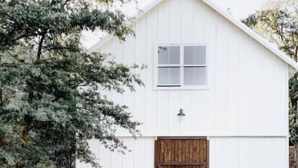 A white barn with a wooden door and a small window.