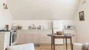 A kitchen with white cabinets, a dining table, and hanging pendant lights.