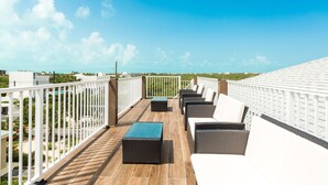 Eine Dachterrasse mit Gartenmöbeln und Blick auf die Stadt unter blauem Himmel.