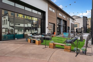 A modern building with a large glass facade, outdoor seating area with furniture, and a well-maintained lawn. - Treehouse #305, Building D by Summit County Mountain Retreats (Silverthorne)